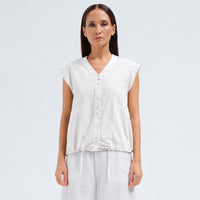 A white cotton shirt by Transit Par Such with a collarless V-neck, button front, cap sleeves and a drawstring hem for a boxy, cropped shape - front view