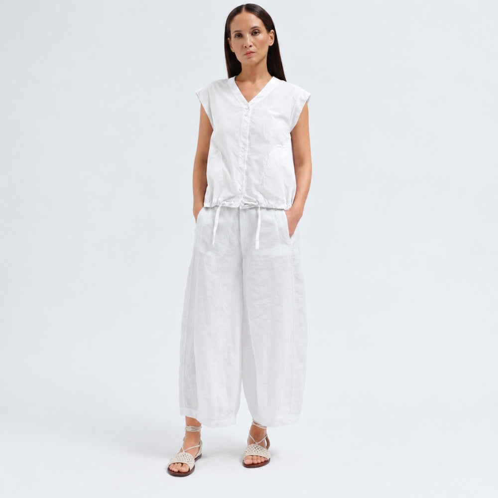 A white cotton shirt by Transit Par Such with a collarless V-neck, button front, cap sleeves and a drawstring hem for a boxy, cropped shape - full model front view