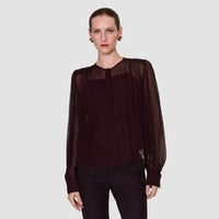 Model wearing the JOSEPH Elisa sheer silk chiffon blouse in mahogany over its camisole