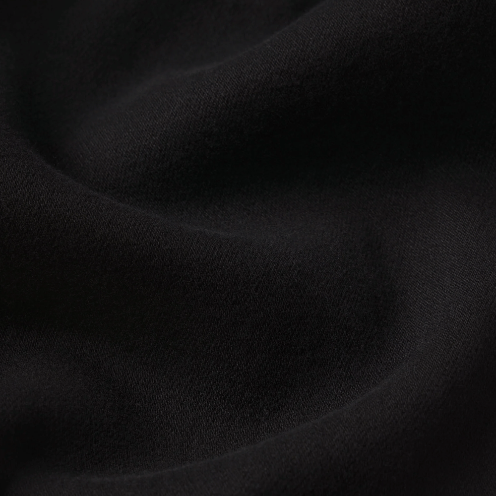 FRAME Le Sleek Straight Jeans in Black at Riada Concept. High-rise ankle-length straight jeans in super-stretch black denim - A close-up of draped black denim with soft folds and a smooth matte texture.