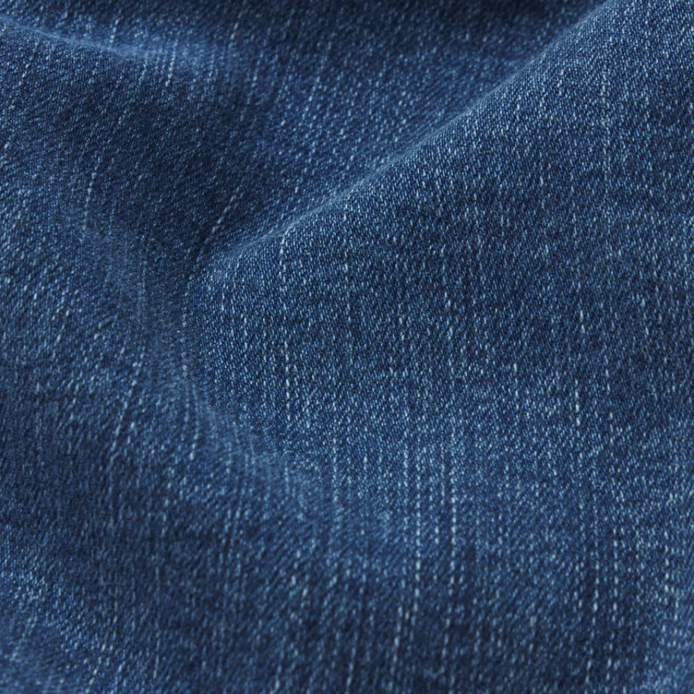 FRAME Le Sleek Straight Jeans in Ease at Riada Concept. High-rise ankle-length straight jeans in super-stretch mid-blue denim - close-up of dark blue denim fabric with a visible twill weave and soft folds.