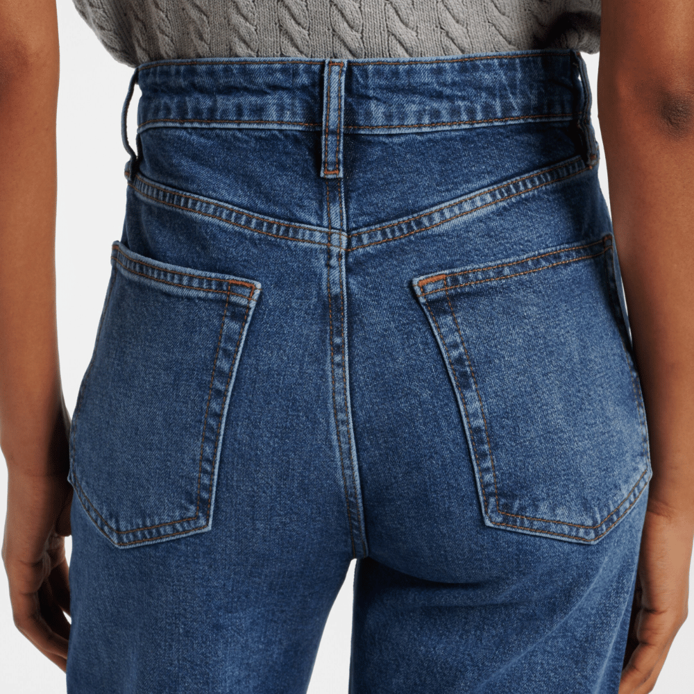 Close-up of FRAME The Arrow jeans in Rival at Riada Concept. High-rise blue bootcut jeans in comfort-stretch denim with a 33-inch inseam - back view showing waistband and back pockets