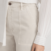 Close-up of model wearing the FRAME The Bow Cargo Jeans in Flax at Riada Concept. High-rise rigid denim with flat utility pockets and a sculpted barrel leg - white pinstriped shirt tucked in, showing the waistband, button, belt loop, and front pocket area.