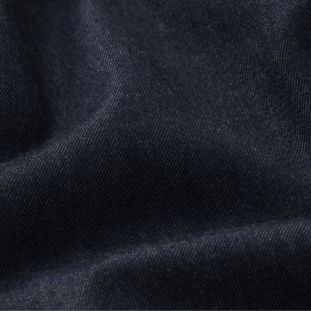 Close-up of dark navy blue fabric with a fine woven texture and soft folds - FRAME The Denim Balloon Pant in Rinse at Riada Concept. High-rise balloon jeans in fluid cotton-lyocell denim with a gathered ankle