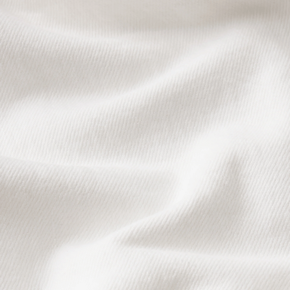 A close-up of white ribbed denim fabric with soft folds and a smooth texture - FRAME The Essential Jean in White at Riada Concept. Mid-rise full-length straight jeans in rigid regenerative cotton denim