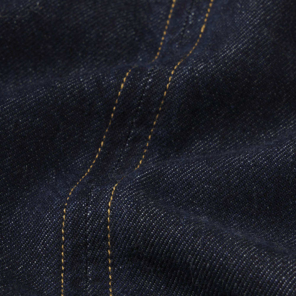 Close-up of FRAME The Form Vest in Rinse at Riada Concept. Sculpted rigid indigo denim waistcoat with princess seams and silver buttons - denim fabric with contrasting yellow stitching running vertically - 