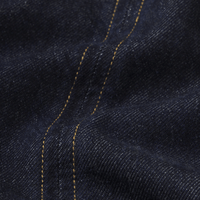 Close-up of FRAME The Form Vest in Rinse at Riada Concept. Sculpted rigid indigo denim waistcoat with princess seams and silver buttons - denim fabric with contrasting yellow stitching running vertically - 