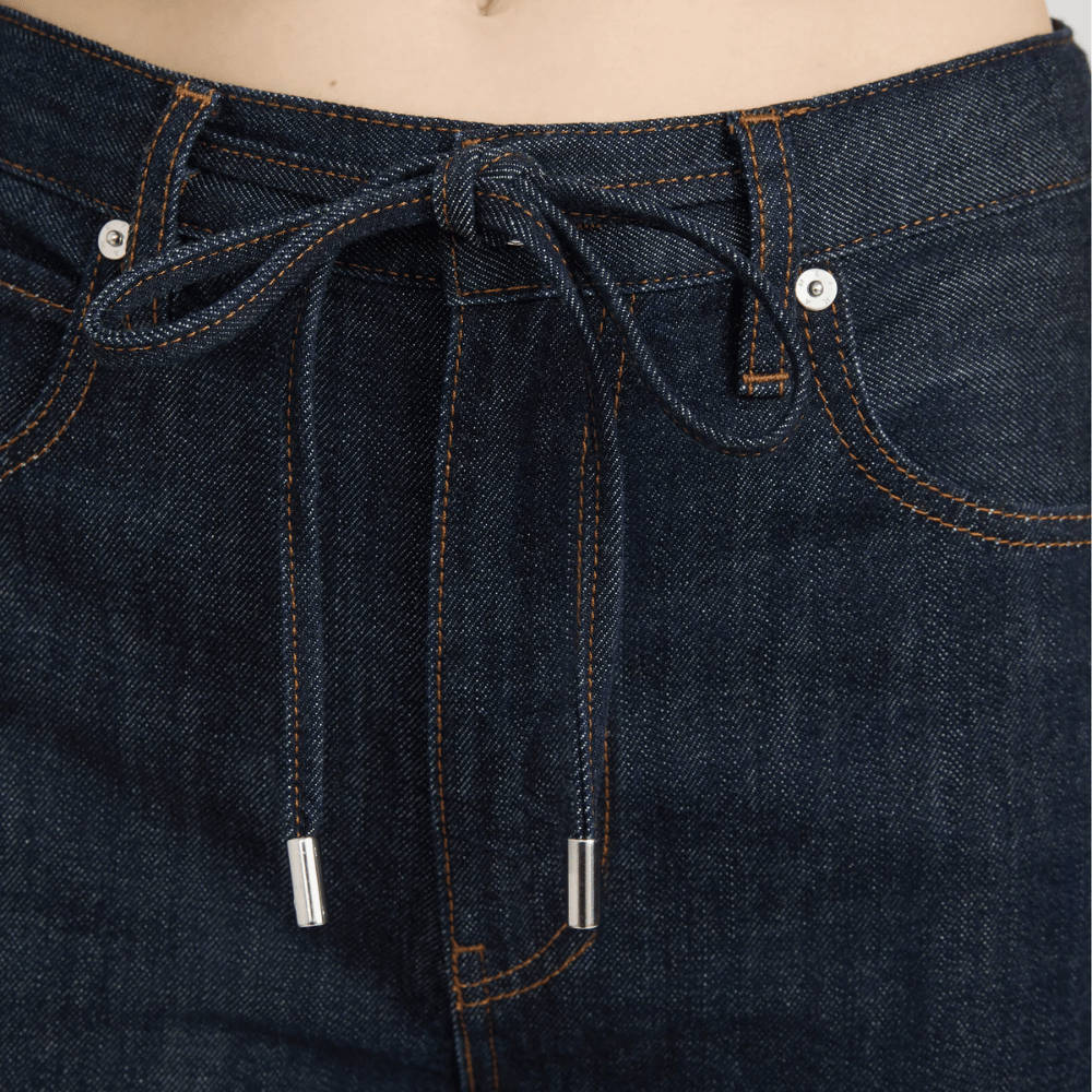 Close-up of FRAME The Off Duty Drawstring Bow Jeans in Rinse at Riada Concept. High-rise fluid denim with a curved leg and drawstring waist - with drawstring and button details.
