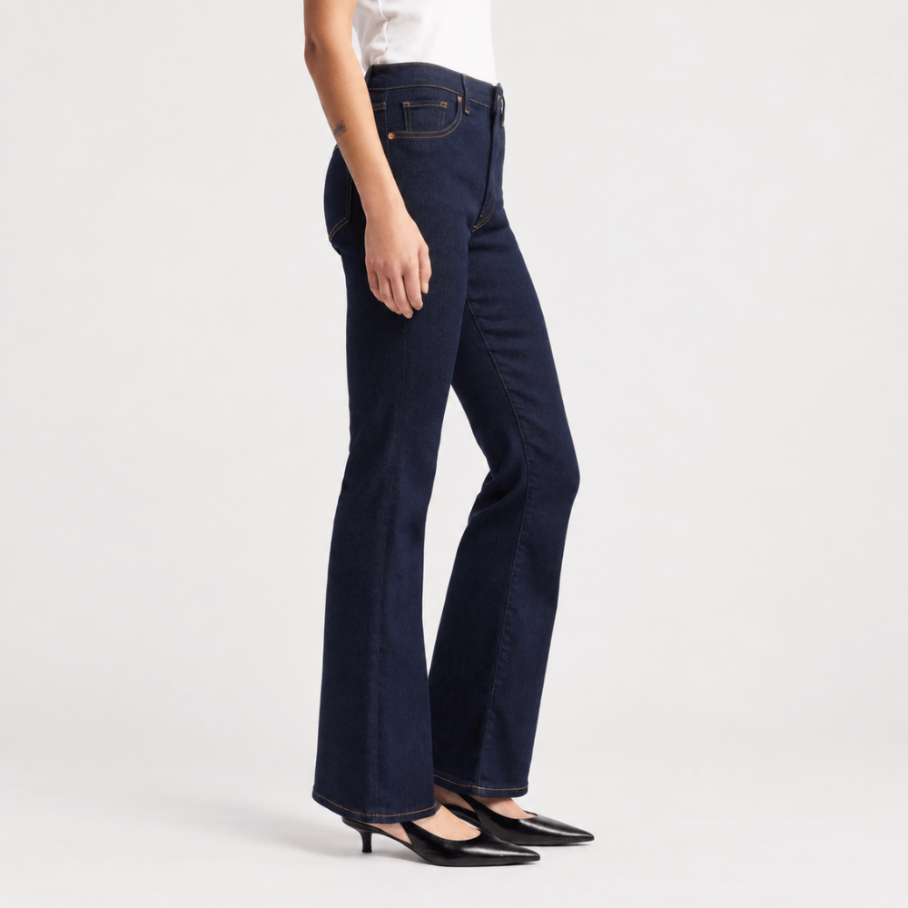 Model wearing FRAME The Reboot Jeans in Stargirl at Riada Concept. High-rise full-length bootcut jeans in dark indigo stretch denim with golden contrast stitching.