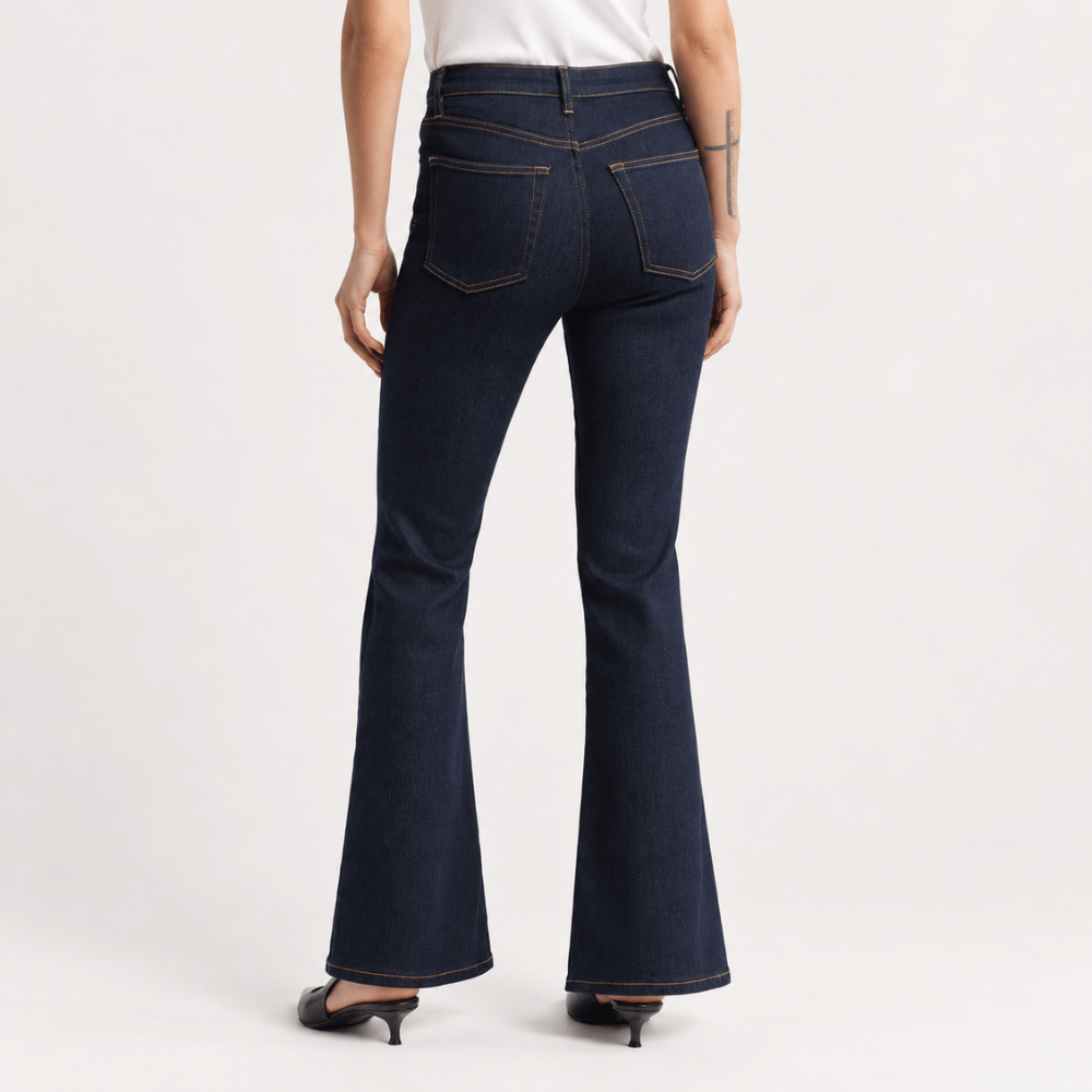 Back view model wearing FRAME The Reboot Jeans in Stargirl at Riada Concept. High-rise full-length bootcut jeans in dark indigo stretch denim with golden contrast stitching.