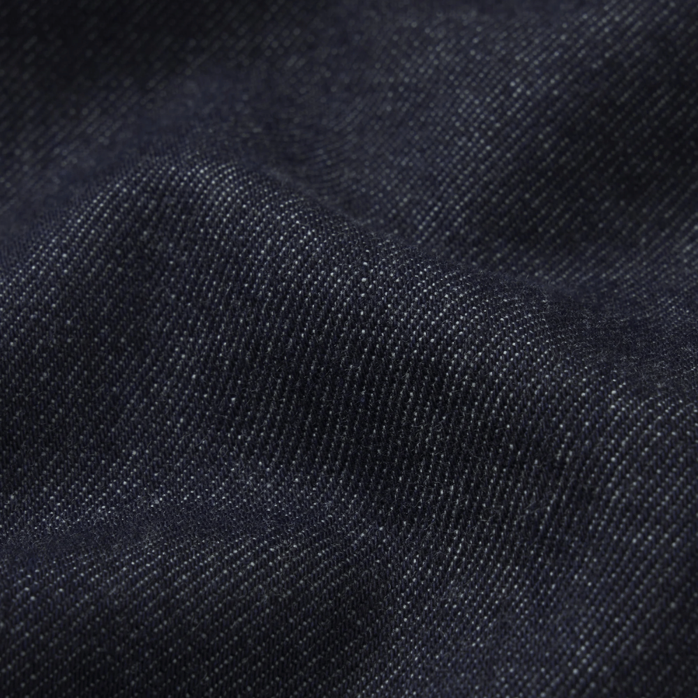 Close-up of dark indigo denim fabric showing the twill weave texture and soft folds - FRAME The Swing Jeans in Rinse at Riada Concept. High-rise cropped wide-leg jeans in rigid dark-indigo regenerative cotton - front view