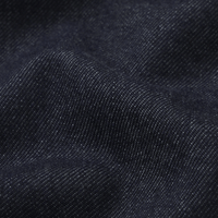 Close-up of dark indigo denim fabric showing the twill weave texture and soft folds - FRAME The Swing Jeans in Rinse at Riada Concept. High-rise cropped wide-leg jeans in rigid dark-indigo regenerative cotton - front view