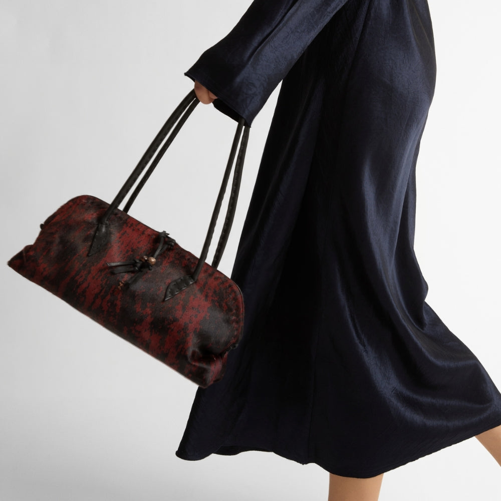 Riada Concept Henry Beguelin’s Bolla Bassa in streaked wine pony-hair calf: a low, rounded shoulder bag with black leather handles and beaded pulls, handcrafted in Italy - styled model