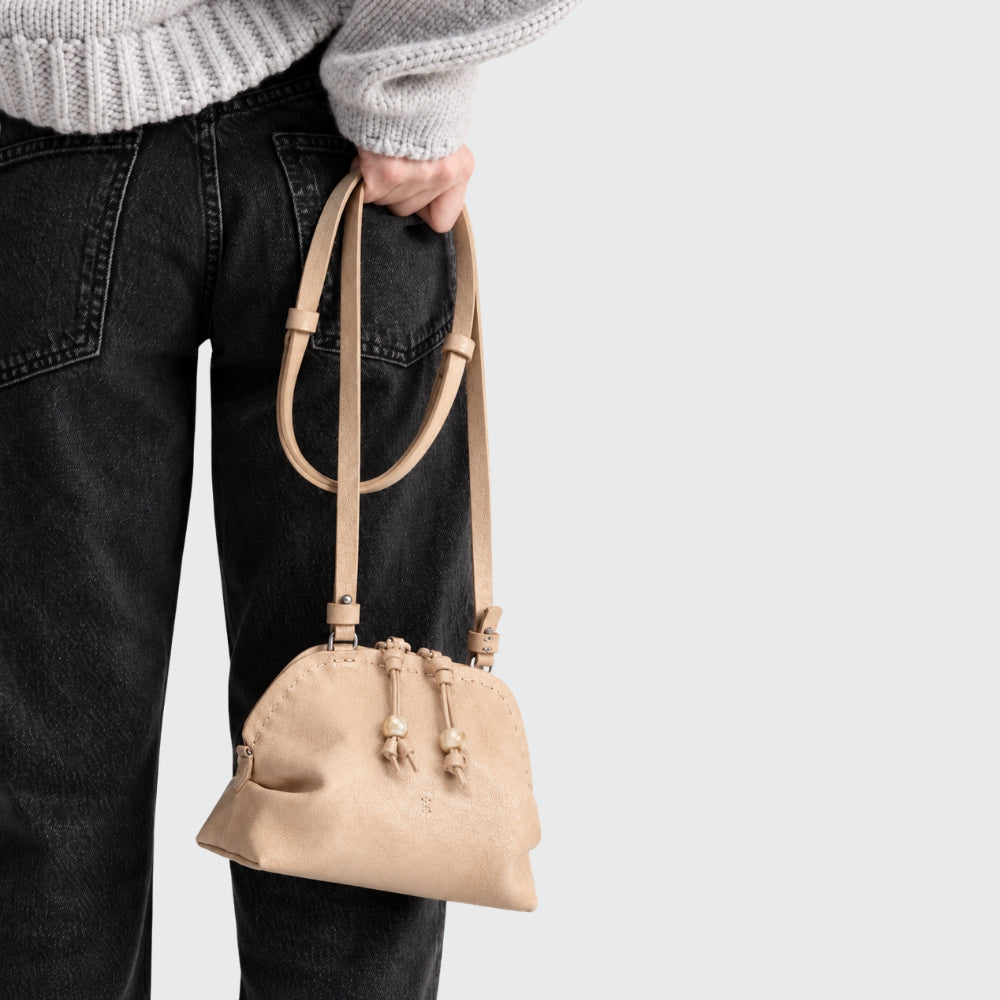Riada Concept A compact Henry Beguelin Bolla crossbody in camel Old Iron lambskin, with a two-way zip and a slim adjustable leather strap - model view