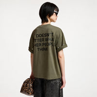 Riada Concept Essentiel Antwerp Kourse T-shirt in khaki organic cotton, scattered with silver-tone studs and printed with slogans on the front and back. Relaxed fit - model back view cropped