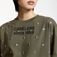 Riada Concept Essentiel Antwerp Kourse T-shirt in khaki organic cotton, scattered with silver-tone studs and printed with slogans on the front and back. Relaxed fit - model neck line close up