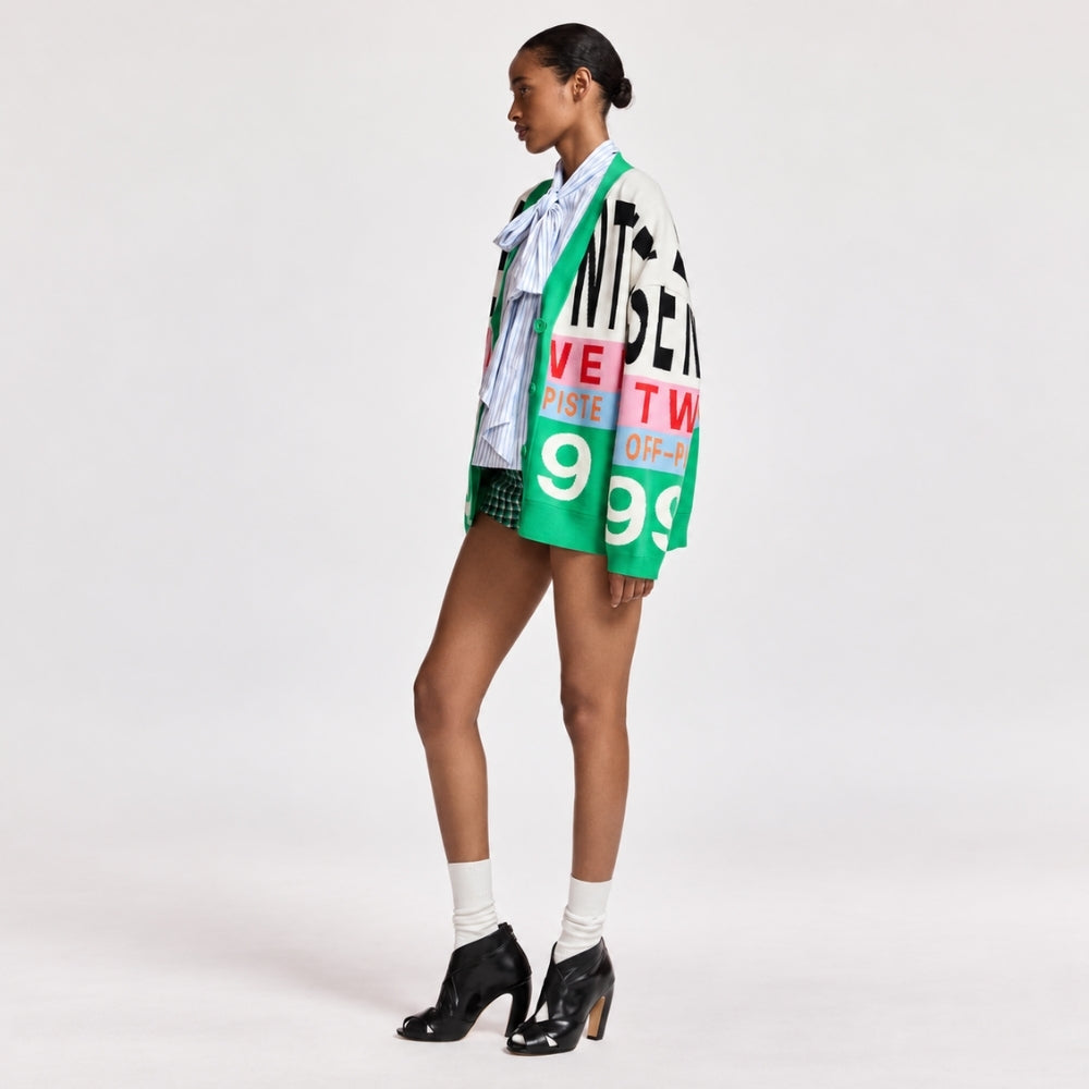 Riada Concept Essentiel Antwerp Kreezer V-neck cardigan with oversized logo intarsia in cream, pink, sky blue and green. Relaxed fit. Model styled angle view