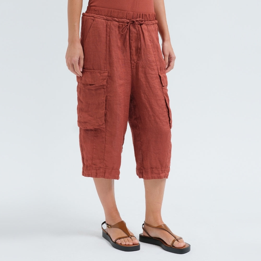 Wide linen cargo Bermuda shorts by Transit Par Such in brick, falling below the knee, with flap cargo pockets and a drawstring elastic waist - angle view