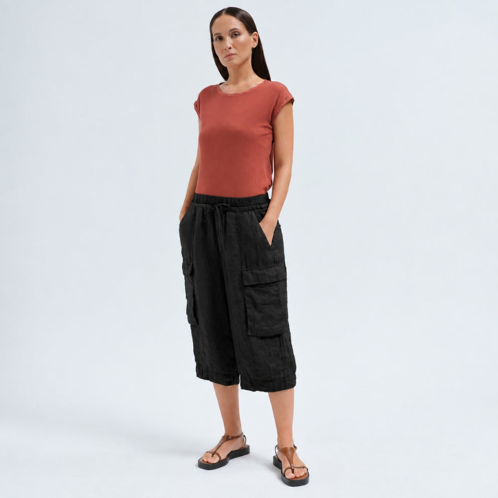 Wide linen cargo Bermuda shorts by Transit Par Such in black, falling below the knee, with flap cargo pockets and a drawstring elastic waist - model front view
