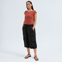 Wide linen cargo Bermuda shorts by Transit Par Such in black, falling below the knee, with flap cargo pockets and a drawstring elastic waist - model front view