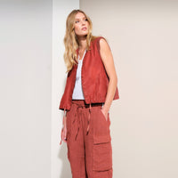 Wide linen cargo Bermuda shorts by Transit Par Such in brick, falling below the knee, with flap cargo pockets and a drawstring elastic waist - model campaign shot styled