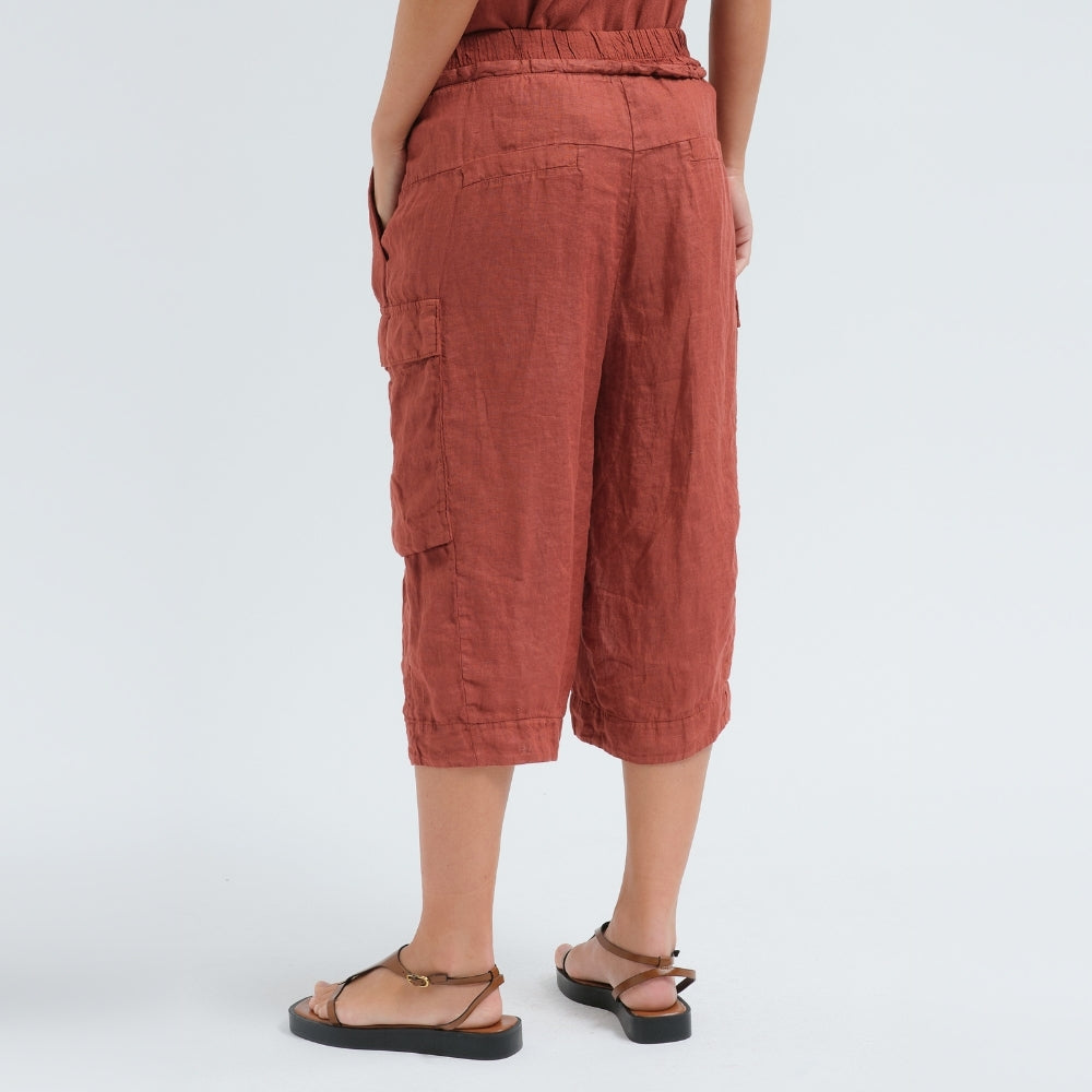 Wide linen cargo Bermuda shorts by Transit Par Such in brick, falling below the knee, with flap cargo pockets and a drawstring elastic waist - back view