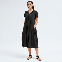 A below-the-knee V-neck dress by Transit Par Such in black stretch cotton, with a high-cut waist, cuffed short sleeves and side pockets - front view with pockets