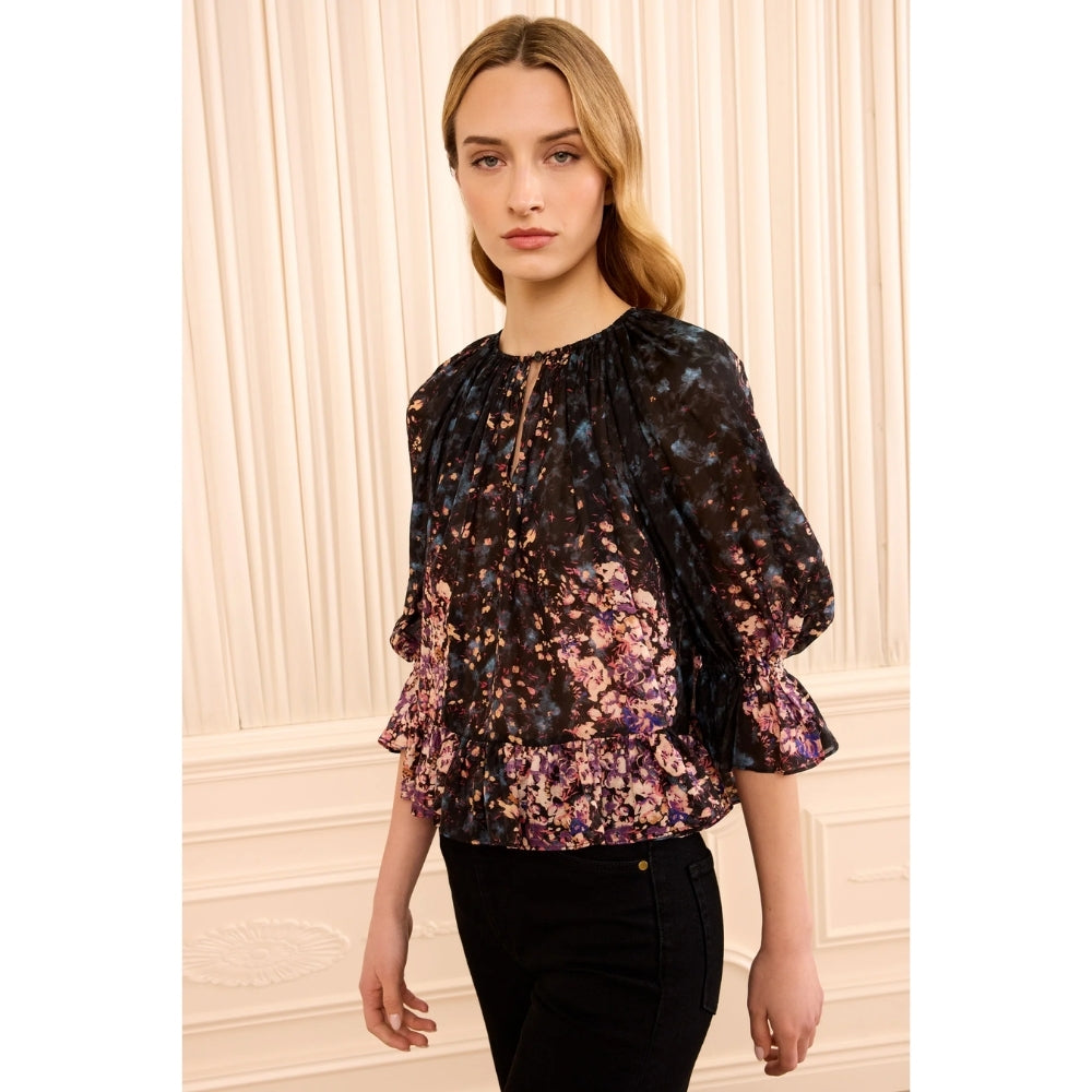 Riada Concept Ulla Johnson Elise silk jacquard blouse in a black floral bouquet print, with ruffles at the sleeves and hem - styled model - angle view