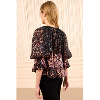 Riada Concept Ulla Johnson Elise silk jacquard blouse in a black floral bouquet print, with ruffles at the sleeves and hem - styled model - back view
