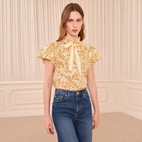 Riada Concept Ulla Johnson Estela cotton poplin top in a pale yellow print, with bubble sleeves and a ruffled tie neck - styled model front view 