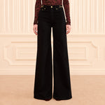 Ulla Johnson Valory high-rise flare jeans in black stretch denim with gold horsebit hardware. Shop at Riada Concept, shipping Australia-wide and worldwide.