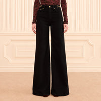 Ulla Johnson Valory high-rise flare jeans in black stretch denim with gold horsebit hardware. Shop at Riada Concept, shipping Australia-wide and worldwide.