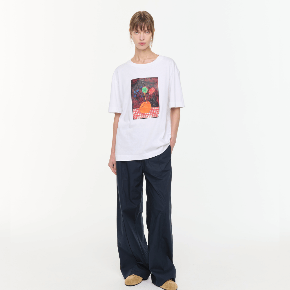 Plan C Vase Print Cotton T-Shirt in Optical White with multicolour floral vase artwork styled on model with relaxed black trousers